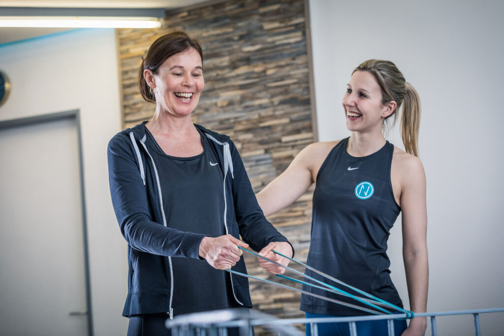 Trainerin begleitet eine Frau beim Training mit dem Widerstandsband