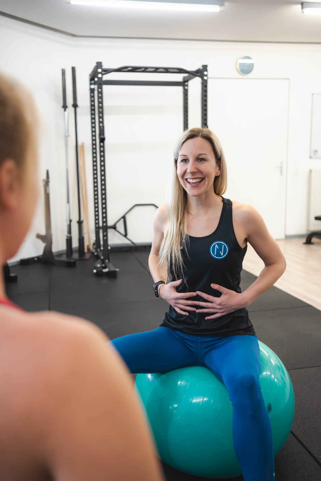 Trainerin zeigt eine Übung für Beckenboden und Körpermitte auf dem Gymnastikball